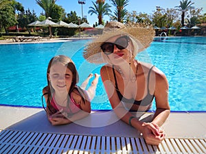 Happy child and woman playing in swimming pool. Summer vacation concept