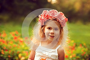 Happy child in wreath of flowers outdoors in summer park