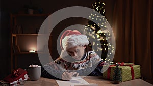 Happy child writing letter for Santa Claus before sending by mail. Christmas traditions, joy and holiday spirit concept