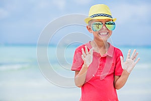 Happy child in yellow hat and sunglasses on beach. Summer vacation concept