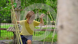 Happy child in a yellow teashirt, school boy enjoys activity in a climbing adventure park