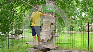 Happy child in a yellow teashirt, school boy enjoys activity in a climbing adventure park