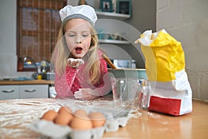 Happy, child or young chef baking in kitchen for learning, practice and making dessert. Fun, chaos and girl mixing flour