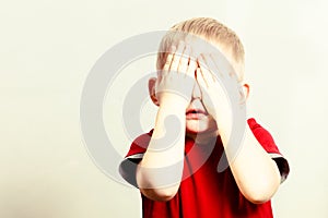 Happy childhood. Blond boy child kid covering face with hands