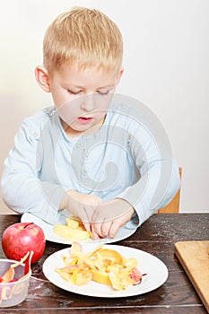 Happy childhood. Boy child kid eating peeled apple fruit. At home.