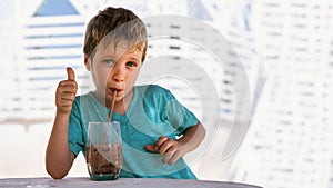 Happy childhood. Boy drinking chocolate tea with ice in hot summer day time. Cute lover of sweets and tasty things