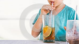 Happy childhood. Boy drinking fruit tea with ice in hot summer day time. Cute lover of sweets and tasty things