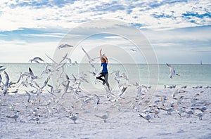 Happy childhood. Child run on the seagulls on the beach, summer time. Cute little boy chasing birds near sea on summer