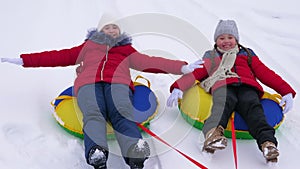 Happy childhood concept. Children`s Christmas holidays outdoors. Happy children have fun riding snow saucer and laugh on