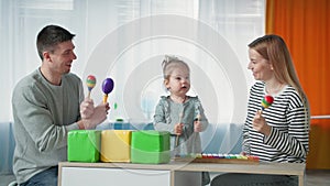 Happy childhood, cute little girl with loving parents have fun playing children's musical instruments while spending time