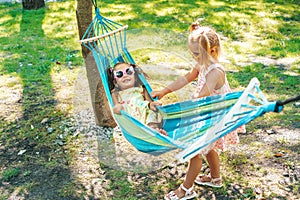 Happy childhood. Five year old girls ride on a hammock in the garden.