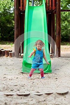 Happy childhood - girl chuting down slide at playground