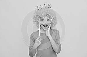 happy childhood. girls birthday party. happy funny kid in curly wig and crown.