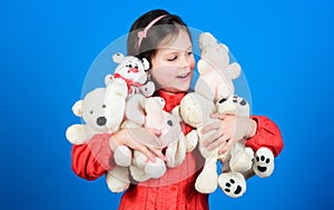 Happy childhood. Little girl play with soft toy teddy bear. Lot of toys in her hands. Childhood concept. Collecting toys