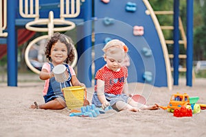 Caucasian and hispanic latin babies children sitting in sandbox playing