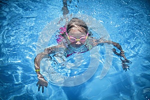 Happy childhood. Young child girl swimming in pool and having fun leisure activity. Horizontal image