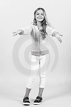 Happy childhood, youth. Small girl smile in sweatshirt, pants, sneakers, fashion. Child smiling with long blond hair
