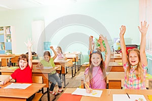 Happy children with arms up sitting in classroom