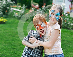 Happy children, boy and girl with face paint in park