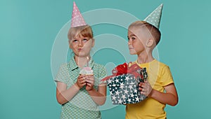 Happy children boy girl siblings friends celebrating birthday blowing candle on cake making a wish