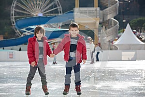 Happy children, boys, brothers with red jackets, skating during