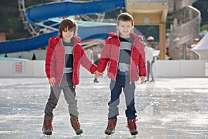 Happy children, boys, brothers with red jackets, skating during