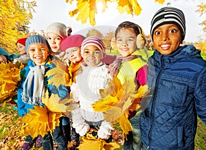 Happy children with bunches of yellow maple leaves