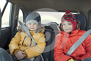 Happy children in the car in the back seat winter trip
