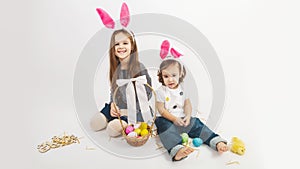 Happy children celebrate Easter. little girls wearing bunny ears enjoying egg hunt. Kids playing with color eggs and flower basket