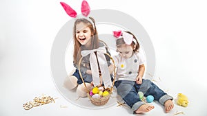 Happy children celebrate Easter. little girls wearing bunny ears enjoying egg hunt. Kids playing with color eggs and flower basket