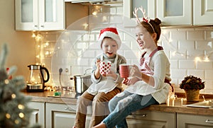 Happy children on Christmas eve,   girl and boy drink hot cocoa drink that they baked together in cozy kitchen at home