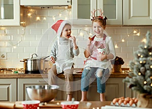 Happy children on Christmas eve,   girl and boy eat cookies that they baked together in cozy kitchen at home