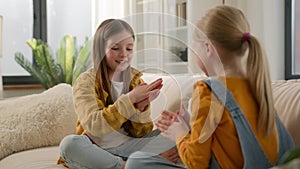 Happy children clapping their hands in living room sofa little cute joyful caucasian kids girls sisters friends playing