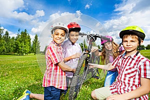 Happy children in colorful helmets repair bicycle