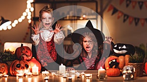 Happy children in costumes of witch and vampire in a dark house