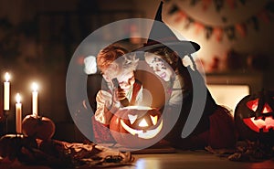 Happy children in costumes of witch and vampire in a dark house in halloween