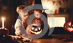 Happy children in costumes of witch and vampire in a dark house in halloween