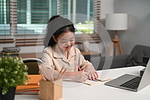 Happy children doing homework, studying online with laptop at home.