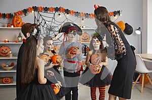 Happy children dressed up in spooky costumes trick or treating at Halloween party