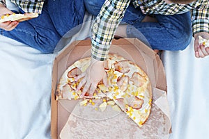 Happy children eating pizza outdoors