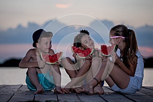 Happy children eating watermelon at sunset time