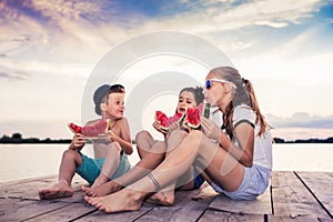 Happy children eating watermelon at sunset time