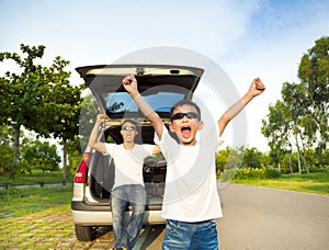 Happy children and father raise arms with their car