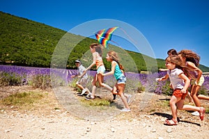 Happy children flying colorful kite in summer