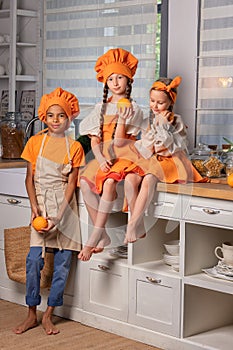 Happy children friends eating fresh orange and playing with fresh mandarin fruits in kitchen at home.