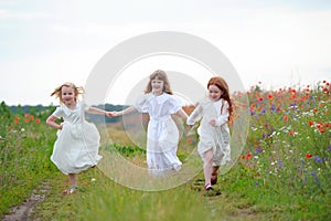 Happy children friends sisters run and play outdoors on the mead