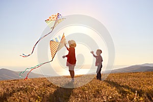 Happy children girl and boy launches a kite at sunset outdoors