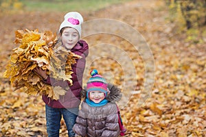 Happy children. girl holding an armful of autumn yellow leaves on the nature walk outdoors
