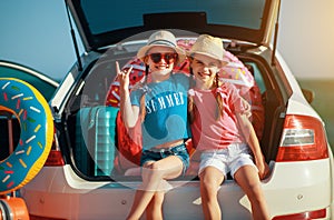 Happy children girls twin sisters on the car ride to summer trip