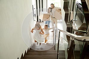 Happy children going upstairs, family with boxes moving in house